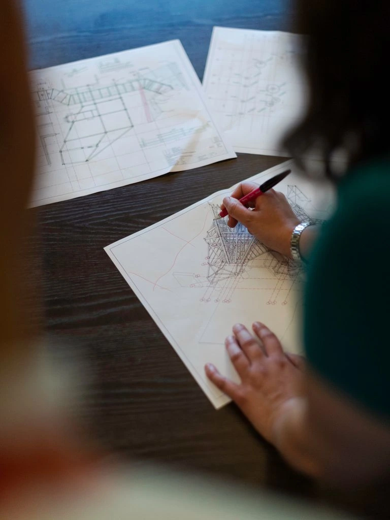 Hand-drawn concept layouts pinned in the studio, with fabric and timber swatches.